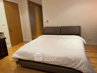 Spacious bedroom with modern bed and wooden flooring in a cozy apartment.
