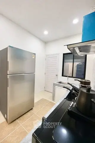 Modern kitchen with stainless steel fridge and sleek appliances in a compact layout.