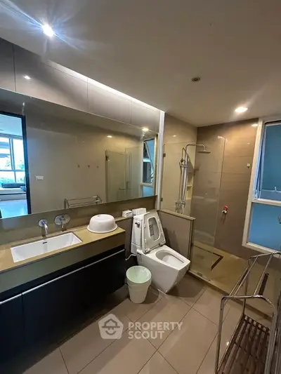 Modern bathroom with sleek fixtures and glass shower enclosure in a contemporary apartment.