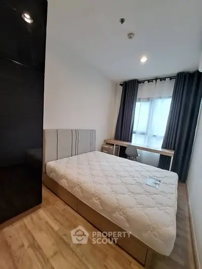 Modern bedroom with wooden flooring, stylish bed, and large window for natural light.