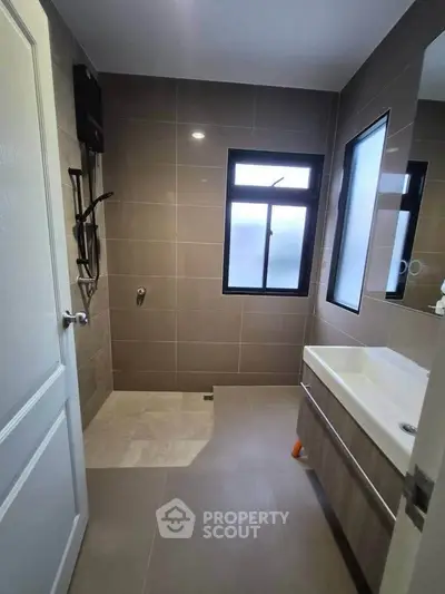 Modern bathroom with sleek tiles and large window for natural light.