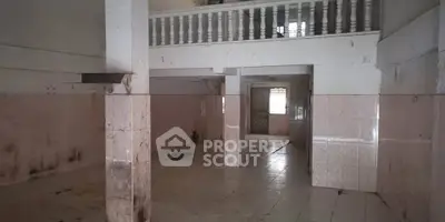 Spacious interior with high ceiling and balcony, ideal for renovation projects.