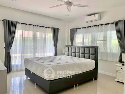 Spacious bedroom with modern furnishings and natural light, featuring a comfortable bed and stylish curtains.