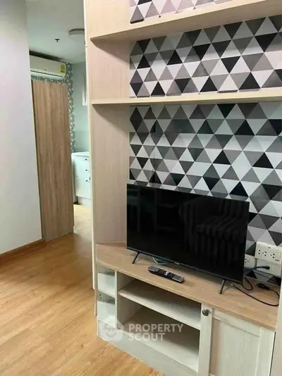 Modern living room with stylish geometric wallpaper and sleek TV setup.