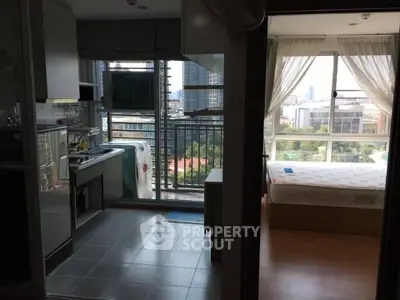 Modern apartment with open kitchen and bedroom, featuring large windows and city view.