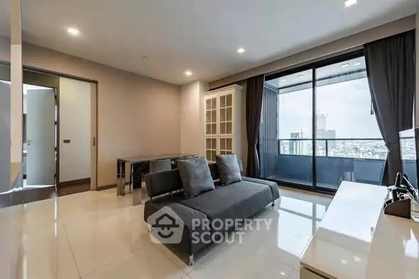 Modern living room with sleek furniture and large windows offering city views.
