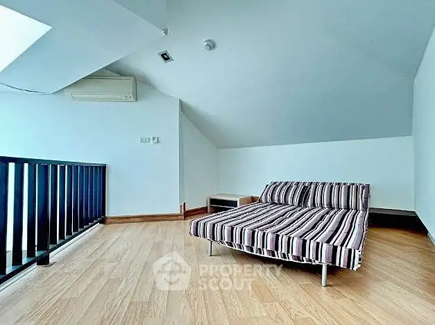 Modern loft space with stylish striped sofa and wooden flooring