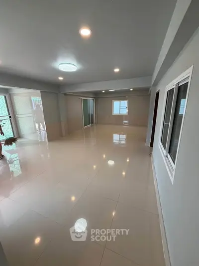 Spacious modern living room with glossy tiled floors and ample natural light.
