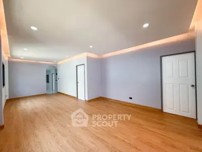 Spacious empty living room with wooden flooring and modern lighting