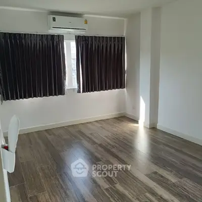 Spacious empty room with wooden flooring and air conditioning, perfect for customization.