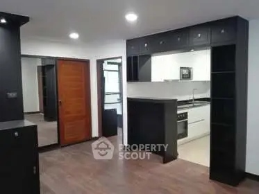 Modern open-layout kitchen with sleek black and white design, featuring built-in oven and ample storage.
