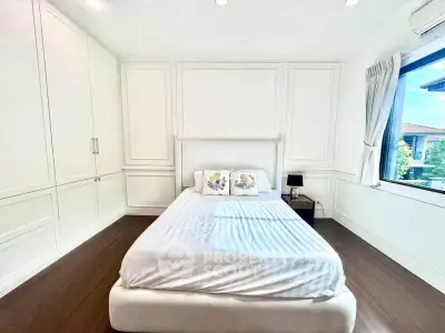 Bright and spacious bedroom with elegant white decor and large window view.
