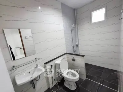 Modern bathroom with sleek design, featuring a toilet, sink, and shower area with stylish tiles.
