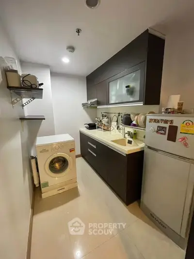 Modern kitchen with sleek cabinets, washing machine, and fridge in compact layout.