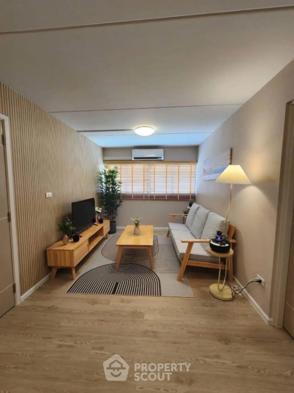 Modern living room with stylish decor and wooden accents, featuring a cozy sofa and entertainment unit.