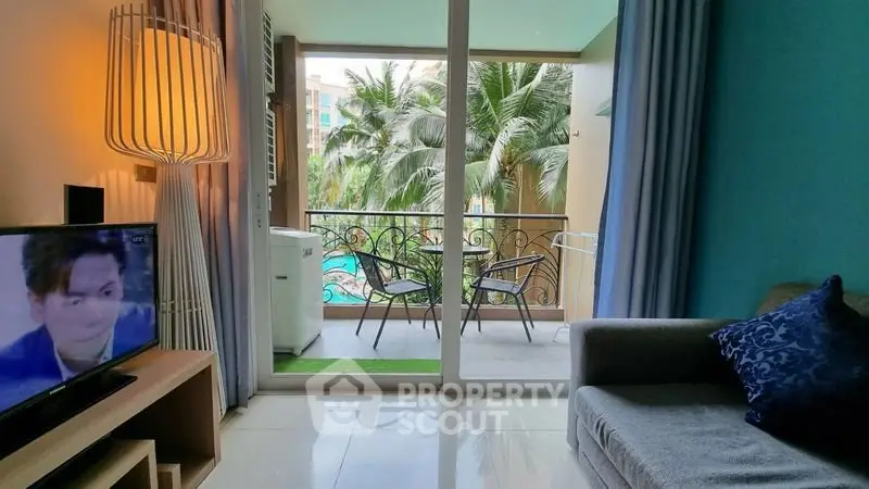 Charming living room with balcony view of lush palm trees and pool, perfect for relaxation.