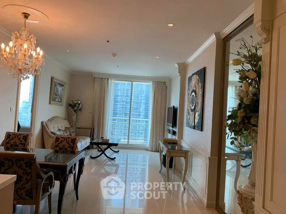 Luxurious living room with elegant chandelier and city view in high-rise apartment.