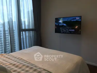 Modern bedroom with wall-mounted TV and large window with sheer curtains.