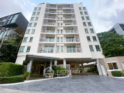 Modern multi-story residential building with lush greenery and spacious entrance.