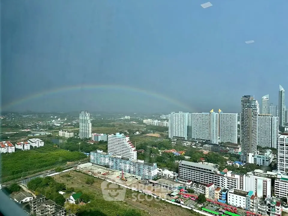 Stunning cityscape view with rainbow over modern high-rise buildings and lush greenery.