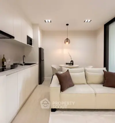 Modern open-layout living room with sleek kitchen and cozy dining area, featuring elegant lighting and contemporary decor.