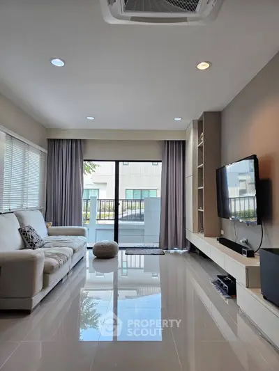 Modern living room with sleek design, large windows, and wall-mounted TV in a stylish home.