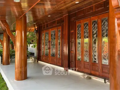 Stunning wooden exterior with intricate glass doors and polished columns, offering a luxurious entrance.