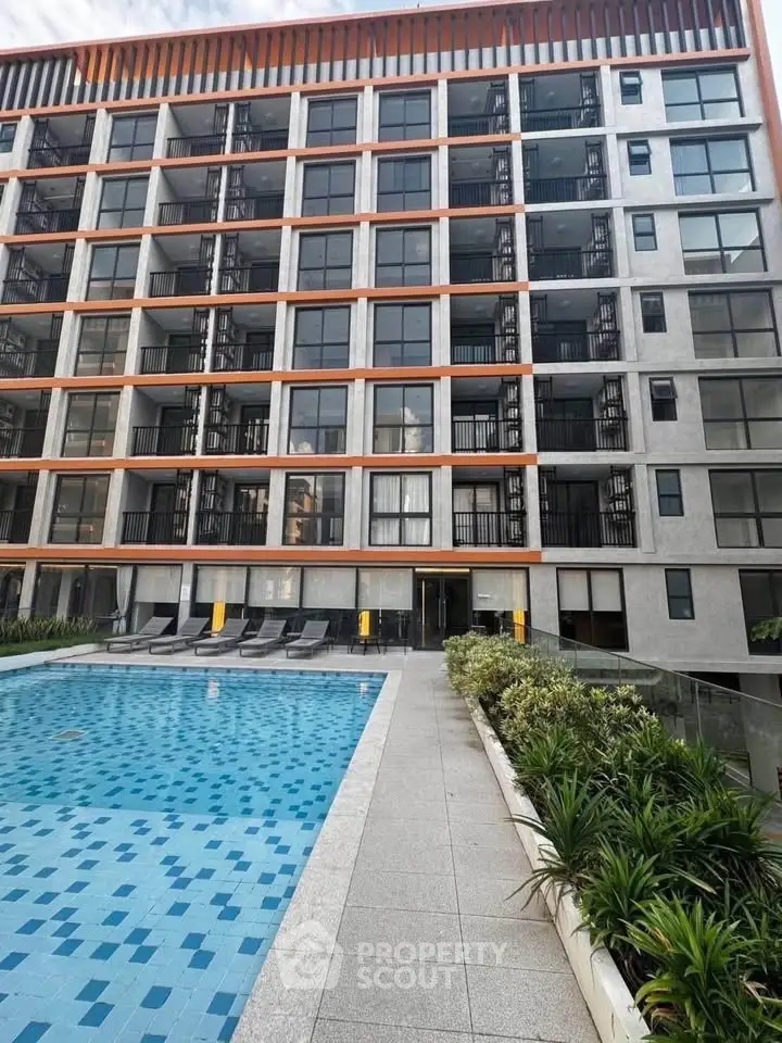 Modern apartment building with pool and sun loungers, ideal for urban living.