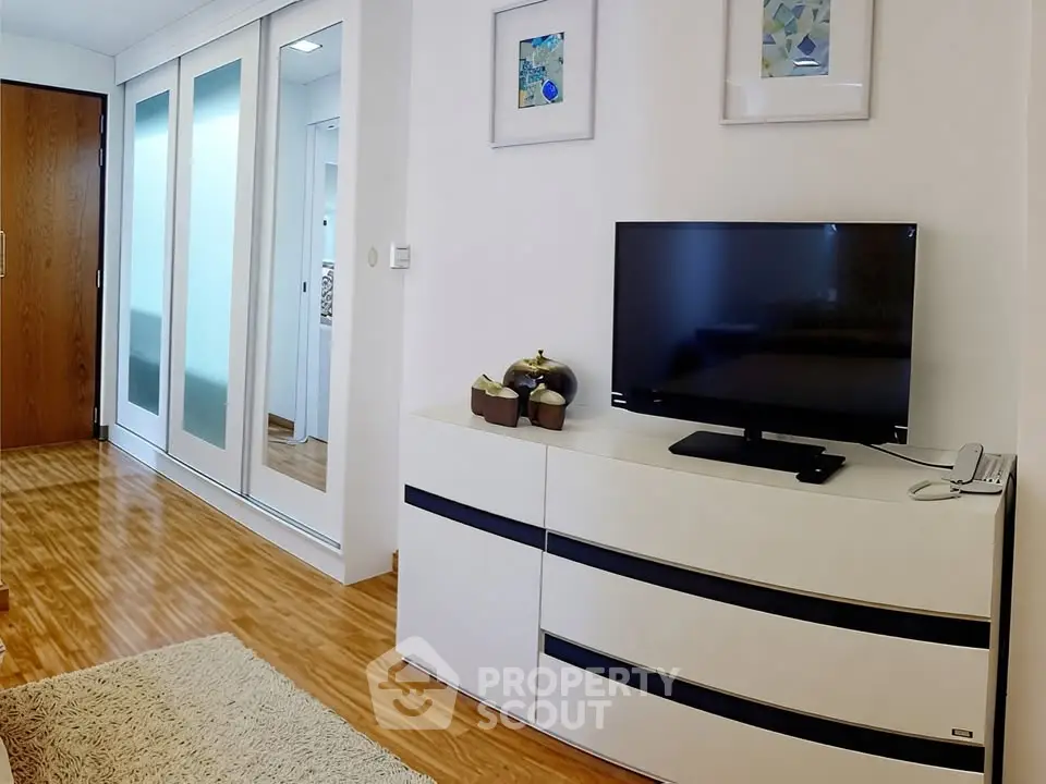 Modern living room with sleek TV stand and mirrored closet doors
