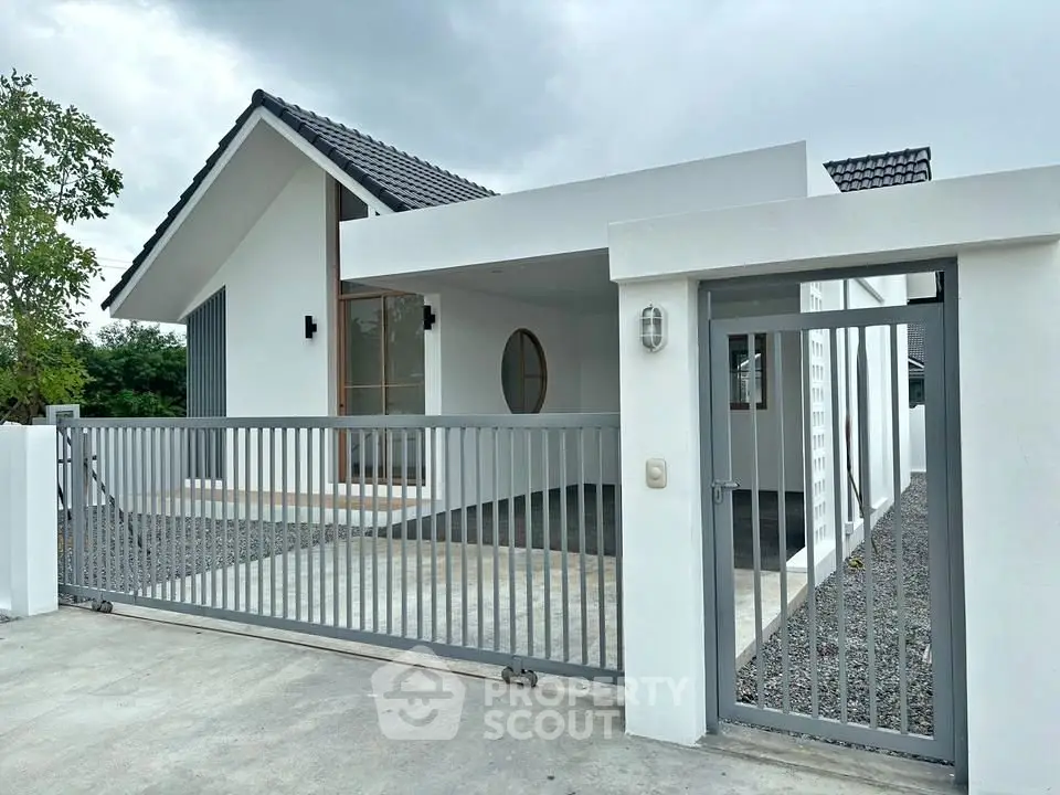 Modern minimalist white house with gated entrance and sleek design.