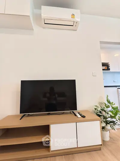 Modern living room with sleek TV setup and air conditioning in a stylish apartment.