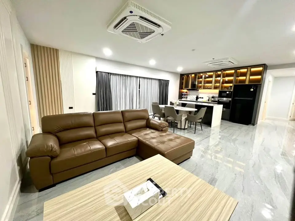 Spacious modern living room with open kitchen, leather sofa, and elegant lighting.