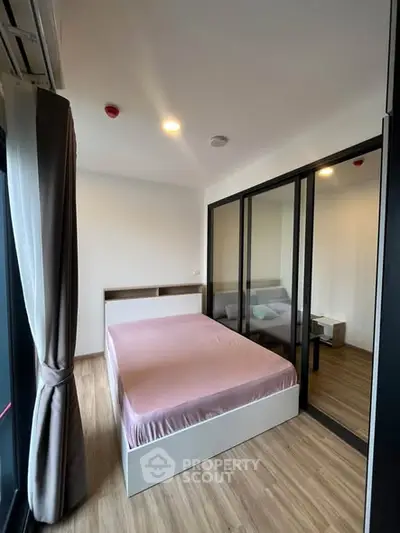 Modern bedroom with large windows and wooden flooring in a stylish apartment.