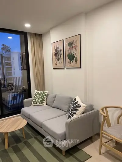 Stylish living room with modern gray sofa, artistic wall decor, and large window view.
