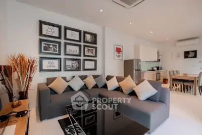 Modern living room with stylish decor and open kitchen layout, featuring a cozy gray sofa and framed wall art.