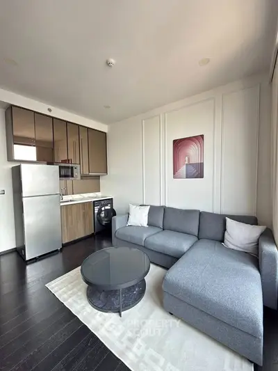 Modern living room with sleek kitchen, featuring a cozy gray sofa and stylish decor.