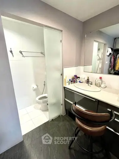Modern bathroom with sleek design, featuring a large mirror and stylish chair, perfect for contemporary living.