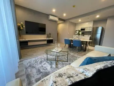 Modern living room with open kitchen, stylish decor, and cozy seating area.