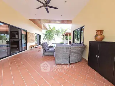 Spacious outdoor patio with stylish furniture and ceiling fan, perfect for relaxation.