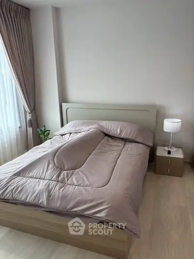 Cozy bedroom with modern decor and natural light, featuring a comfortable bed and stylish nightstand.