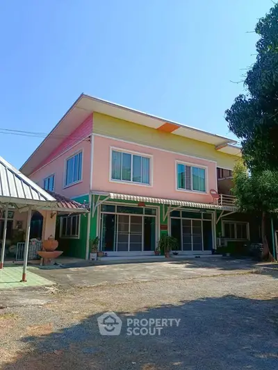 Charming two-story colorful house with spacious driveway and lush greenery.