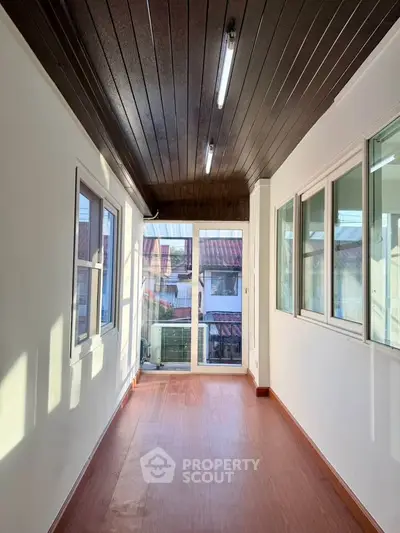 Bright enclosed balcony with wooden flooring and large windows