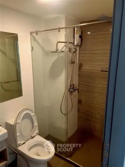 Modern bathroom with glass shower enclosure and sleek fixtures in a contemporary apartment.