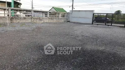 Spacious gravel parking area with secure gated entrance and boundary walls.