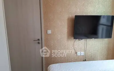 Cozy bedroom with wall-mounted TV and elegant wallpaper, perfect for modern living.