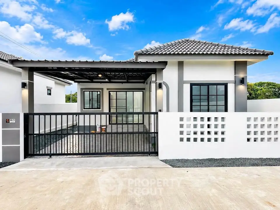 Modern single-story house with gated entrance and stylish facade under a clear blue sky.