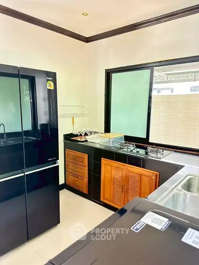 Modern kitchen with sleek black appliances and gas stove, featuring elegant wooden cabinetry and ample natural light.