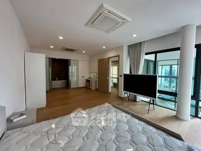 Spacious modern bedroom with large windows and wooden flooring in luxury apartment