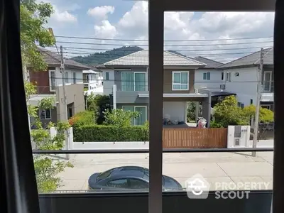 Scenic view from window overlooking suburban houses and street with parked car.