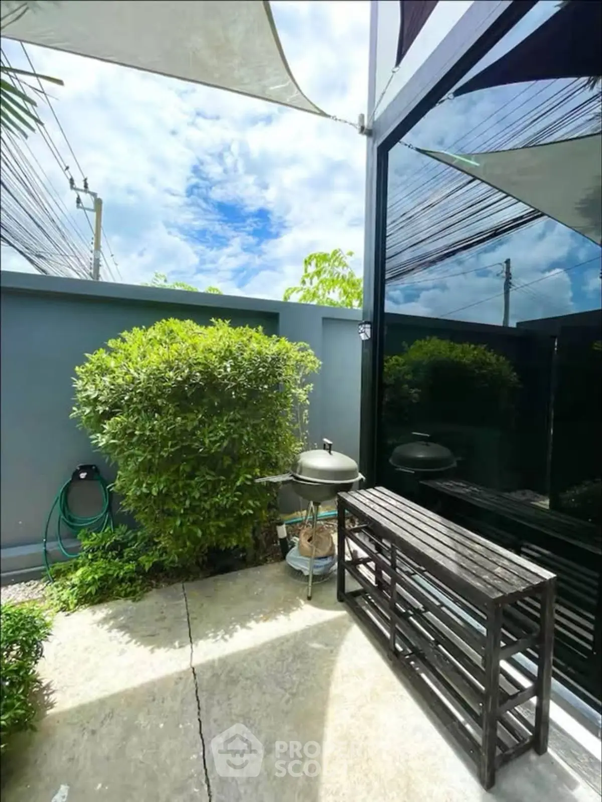 Charming outdoor patio with BBQ grill and lush greenery, perfect for relaxation and entertaining.